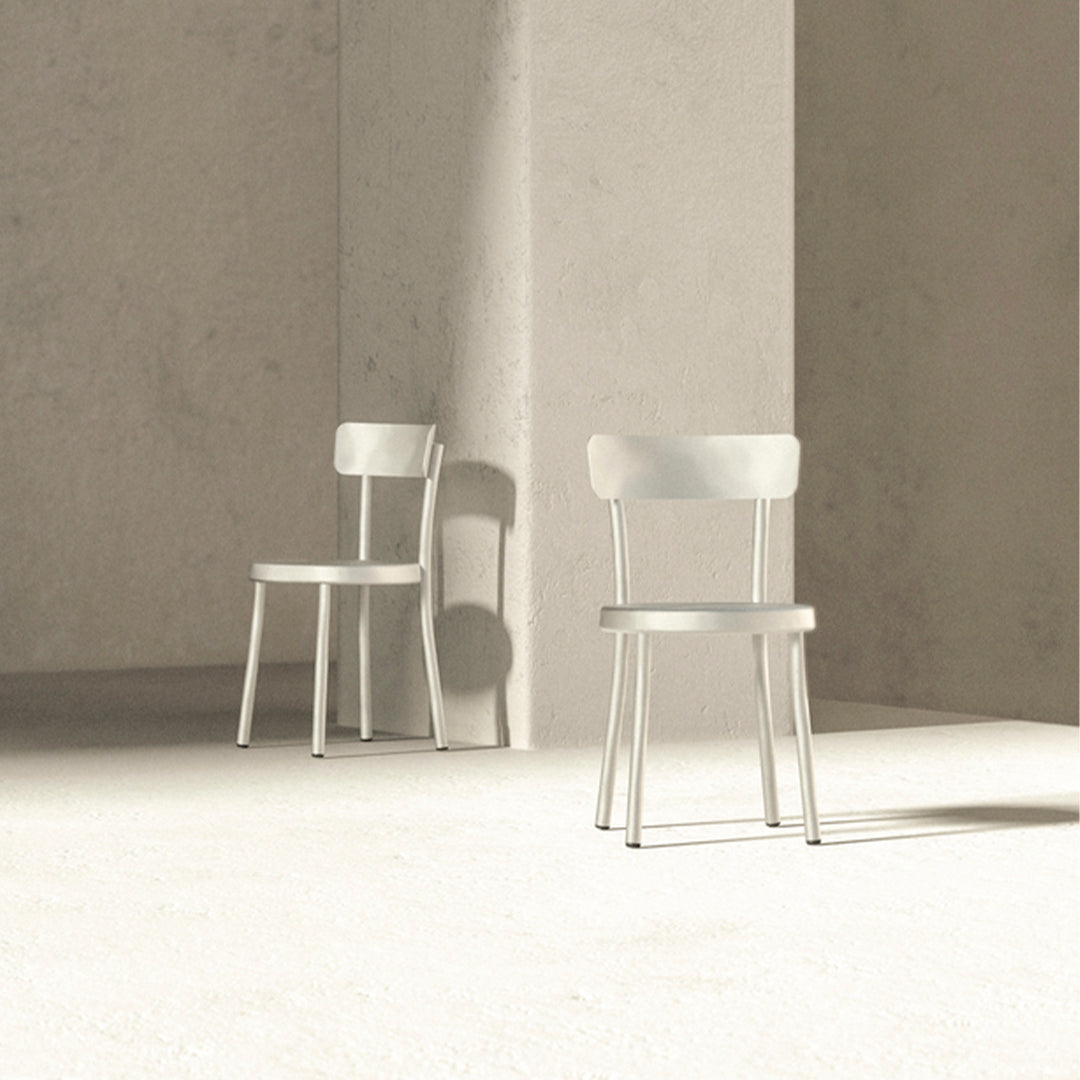 "Stylish minimalistic white wooden chairs against a textured light gray background."