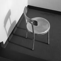 Minimalist black and white chair with sleek design, casting shadows on a dark floor.