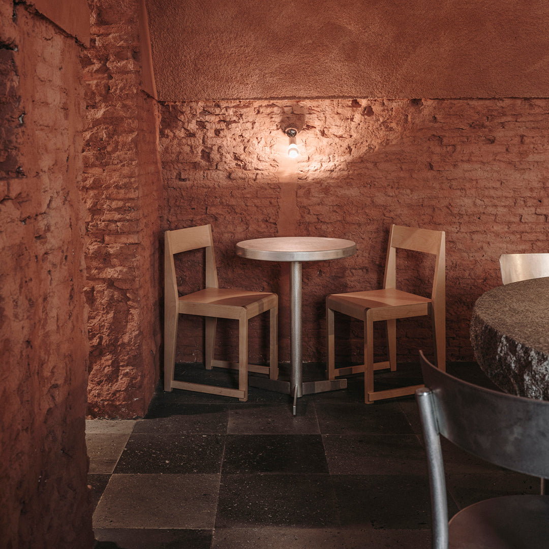 Warm earthy tones with rustic brick walls, wooden chairs, and a round white table, creating a cozy and inviting atmosphere.