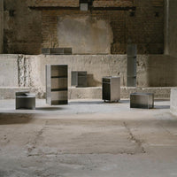 Modern metal furniture in sleek silver finish, exhibiting minimalist design with geometric shapes and clean lines.