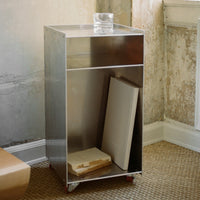 Sleek metallic silver nightstand with minimalist design and subtle reflections, featuring a smooth surface.