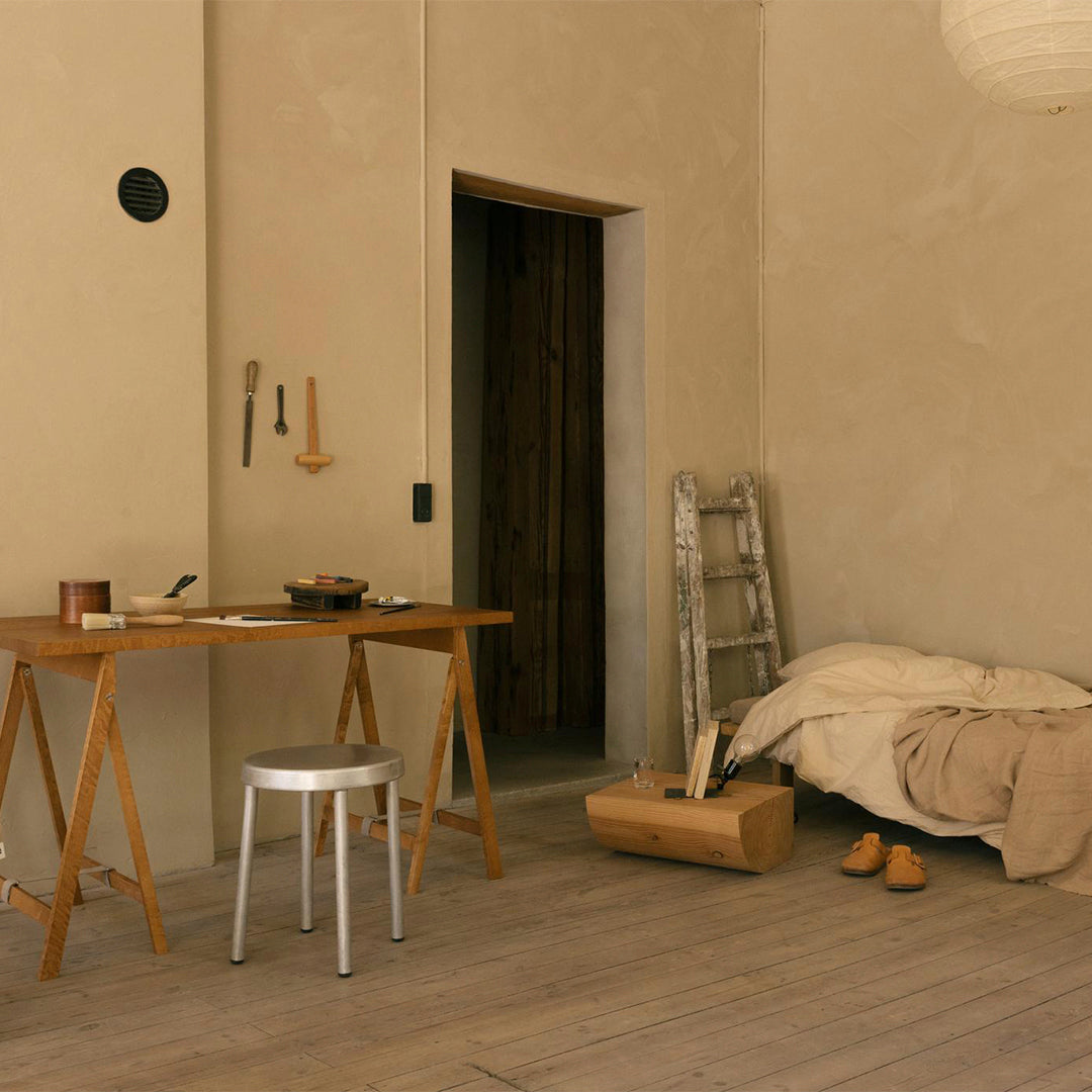 Neutral beige walls, wooden textures, soft beige bedding, gray chair, and subtle earthy tones create a cozy, minimalist aesthetic.