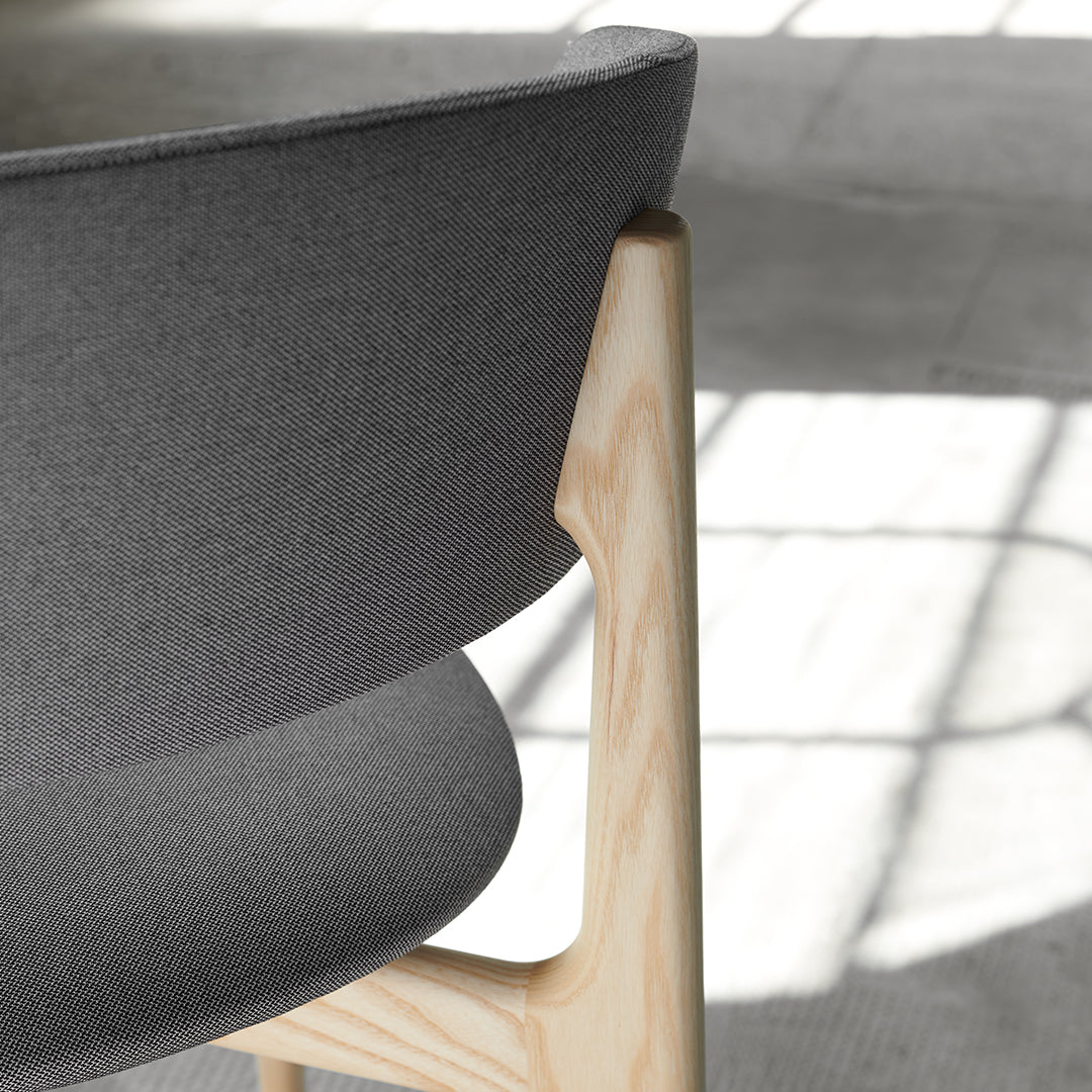 Gray upholstered chair back with a natural wood base, featuring a sleek, modern design and smooth curves.