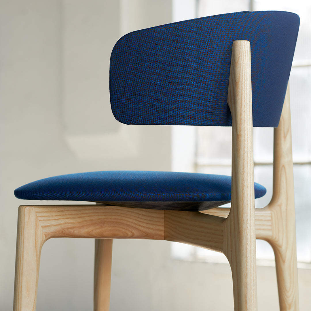 Navy blue cushioned chair with a light wood frame, featuring a minimalist design and smooth contours.
