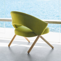 Lime green upholstered chair with a curved design and light wooden legs, against a backdrop of blue water.