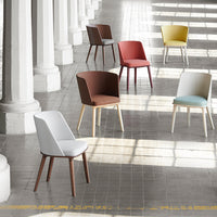 Colorful modern chairs in white, brown, red, yellow, and blue, arranged in a sunlit, spacious hallway.