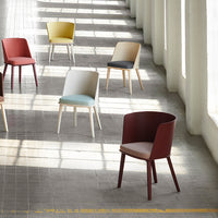 Colorful modern chairs in red, yellow, beige, grey, and blue arranged in a bright, minimalist space.