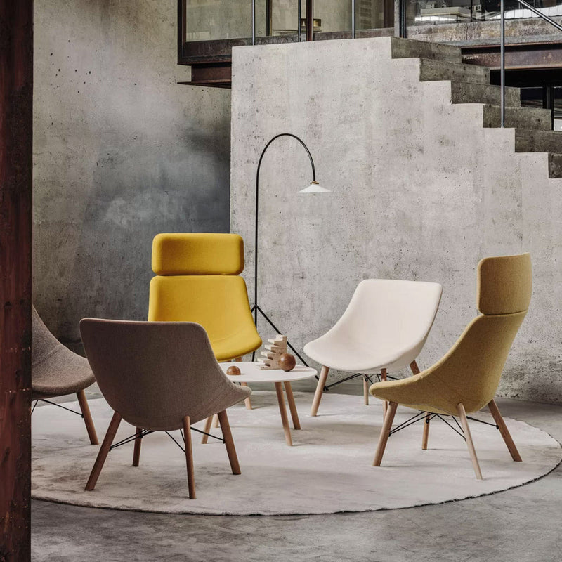Modern lounge chairs in soft beige, yellow, and grey, featuring sleek designs on a circular grey rug.
