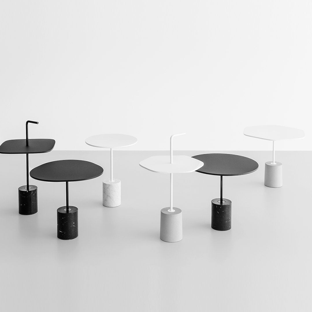 Modern round tables in black and white, featuring sleek bases and smooth circular tops, set against a minimalist backdrop.