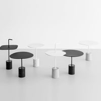 Modern round tables in black and white, featuring sleek bases and smooth circular tops, set against a minimalist backdrop.