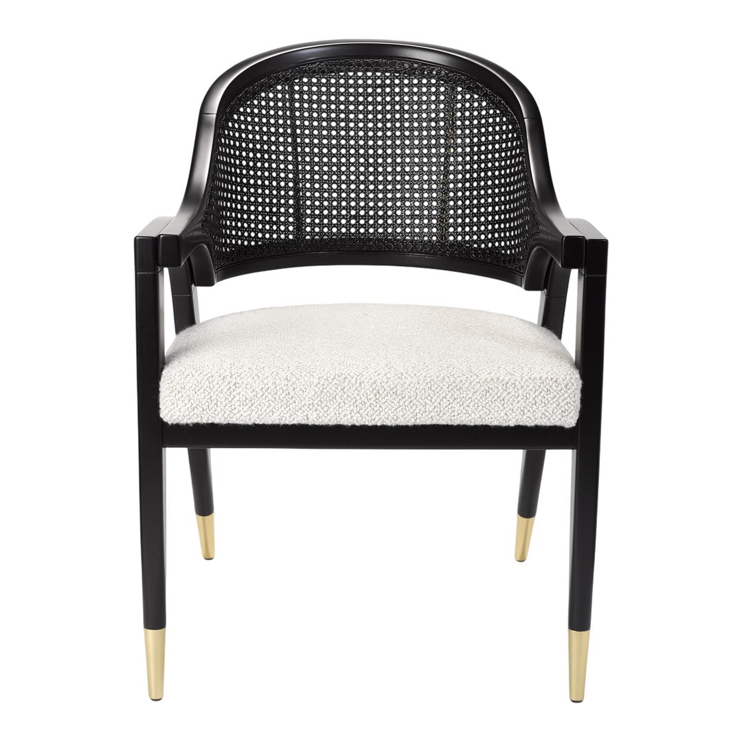 Black rattan chair with cream cushioned seat and gold-tipped legs, showcasing a modern, stylish design.