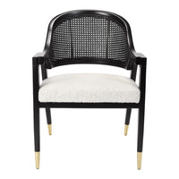 Black rattan chair with cream cushioned seat and gold-tipped legs, showcasing a modern, stylish design.