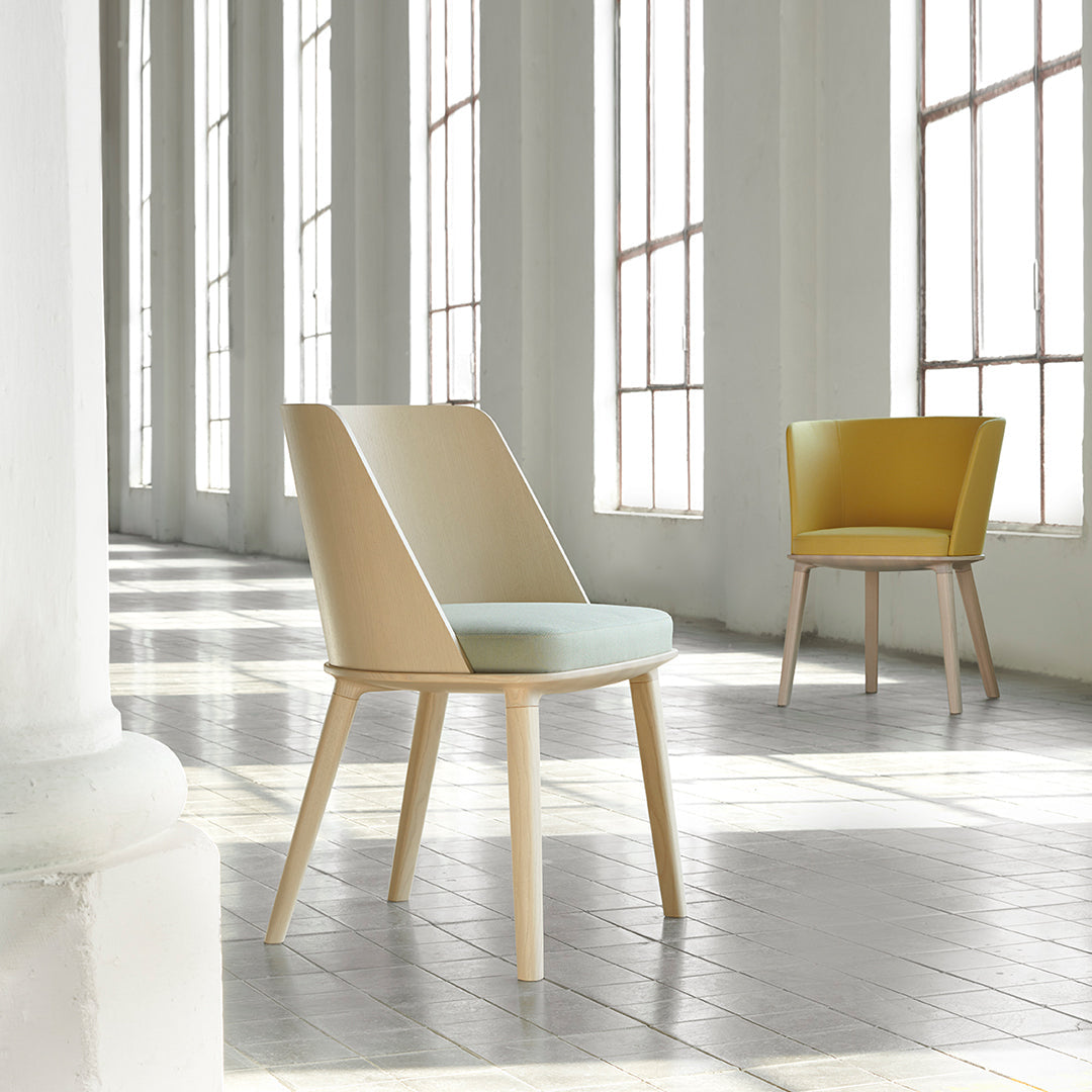 Modern chairs featuring soft beige and mint green upholstery with wooden legs, set against a bright, airy backdrop.