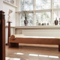 "Modern beige chaise lounge with a textured finish, set against a bright, airy room filled with natural light."