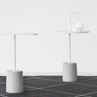 Two modern side tables with white tops and gray bases, set against a geometric black and white patterned rug.
