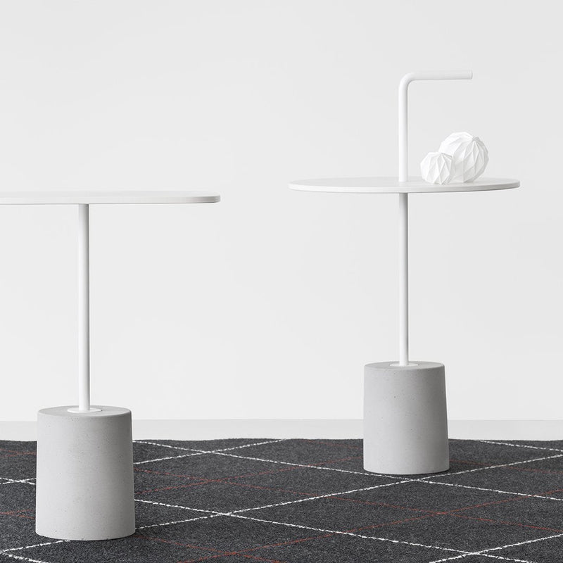 Two modern side tables with white tops and gray bases, set against a geometric black and white patterned rug.