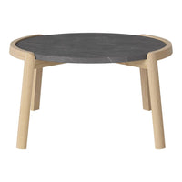 Round black marble top coffee table with natural wood legs, featuring a minimalist design and neutral color palette.