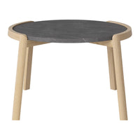 Round table with a sleek black stone top and natural wooden legs in a minimalist design.