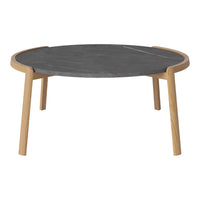 Round coffee table with a sleek black surface and natural wood legs, featuring a minimalist design and smooth curves.
