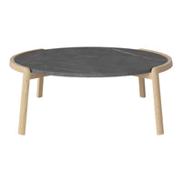 Round coffee table featuring a sleek dark gray surface with natural wood legs. Minimalist design with clean lines.