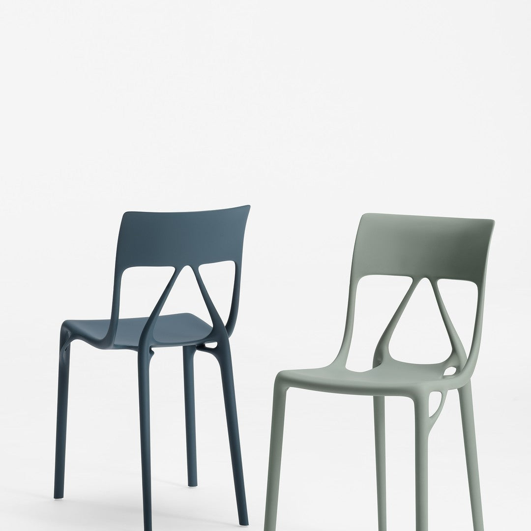 Pair of modern chairs in deep navy and soft sage green, featuring sleek, cut-out designs and smooth finishes.