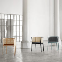 "Three stylish chairs: natural wood, sleek black, and soft blue with woven back patterns in a minimalistic space."