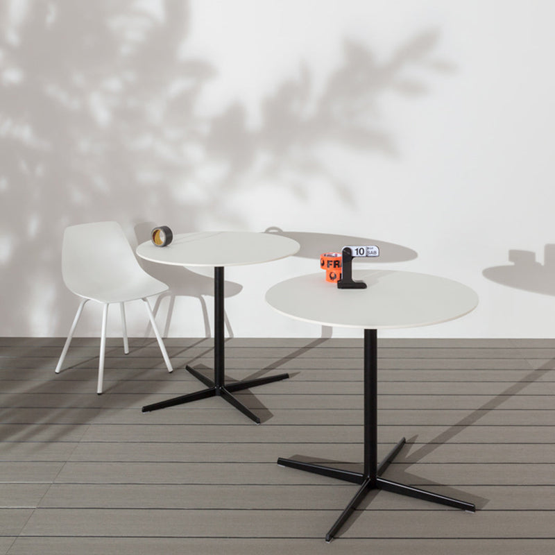 Modern round tables in matte white with black bases, featuring minimalist design and subtle shadow patterns.