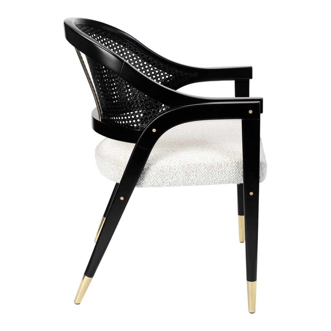 Modern black woven chair with a cream upholstered seat and gold accents on the legs. Elegant and stylish design.