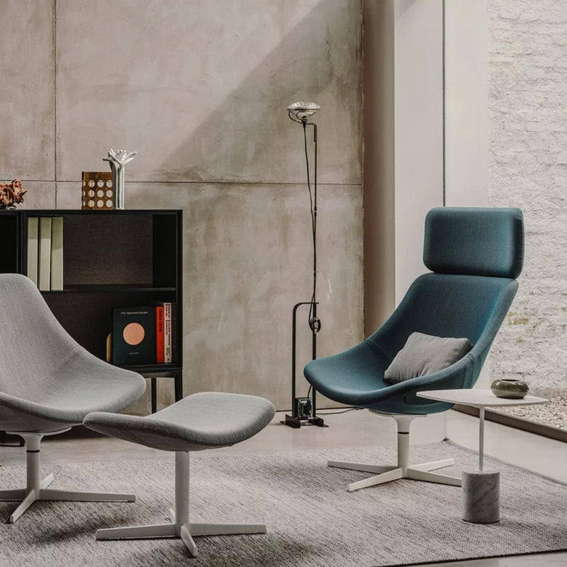 "Modern gray and teal lounge chairs with sleek lines, set against a neutral concrete backdrop and soft rug."