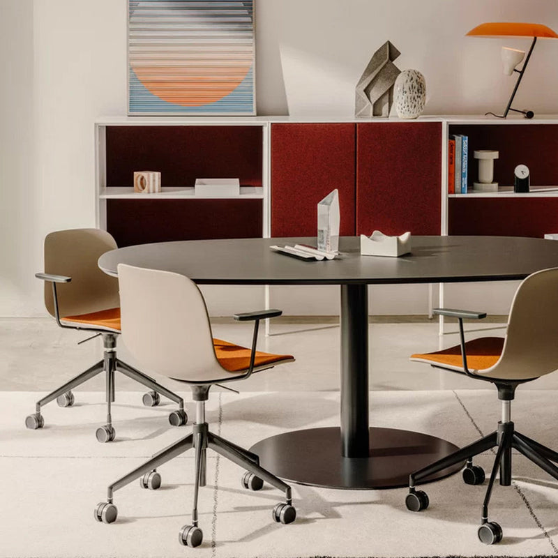 Modern round table with black surface, complemented by gray and orange patterned chairs, set against a neutral background.