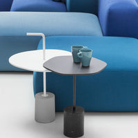 Modern side tables in white and black, featuring sleek designs and textured grey bases, against a vibrant blue backdrop.