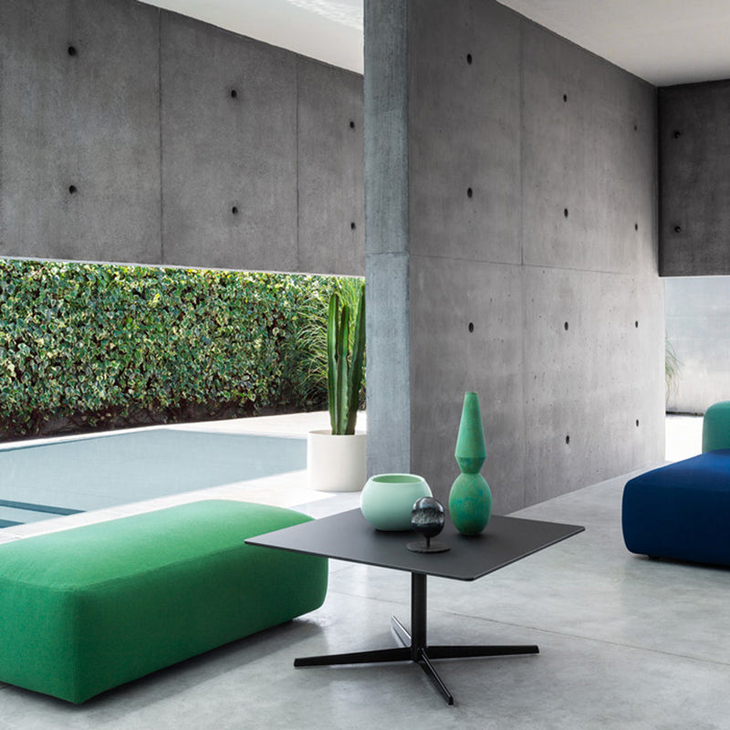 Modern living space featuring vibrant green and blue furniture against a sleek gray wall and lush greenery.
