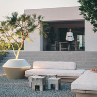 Modern outdoor lounge set featuring neutral beige cushions, natural wood accents, and a sleek white planter.