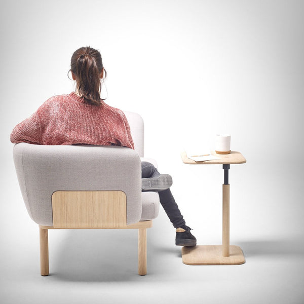 Soft gray chair with light wood accents, paired with a minimalist light-colored side table, creating a cozy vibe.