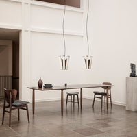 Modern dining room featuring a dark wood table, light wooden chairs, and sleek, minimalistic pendant lights in warm tones.