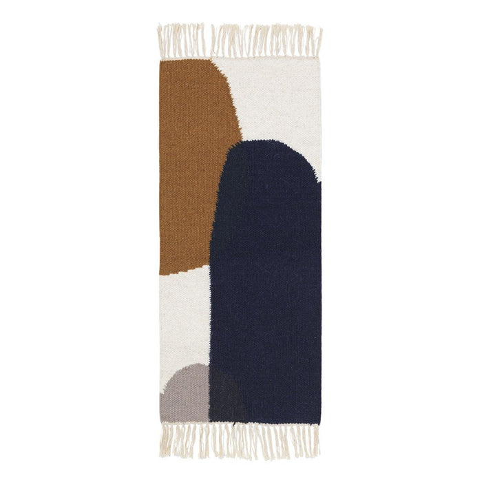 Multicolored woven rug featuring earthy tones like brown and navy, with abstract shapes and fringe edges.