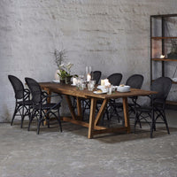 Rustic wooden dining table with dark wicker chairs, featuring natural textures and earthy tones. Perfect for modern decor.
