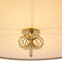 Gold chandelier with intricate circular patterns against a soft beige shade, creating an elegant ambiance.