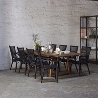 Farmhouse wood dining table with black rattan chairs, featuring a natural wood finish and minimalist design.