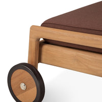 Brown patterned cushion on a wooden frame with a black wheel, showcasing a modern design and natural tones.