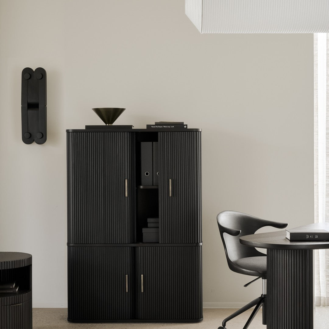 Black ribbed cabinet with gold accents, set against a neutral wall, showcasing a modern, minimalist aesthetic.