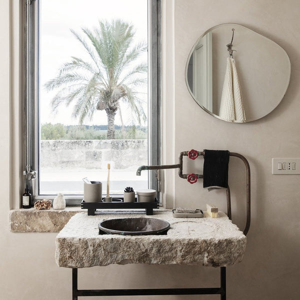 Natural stone sink with white and gray tones, complemented by black accents and minimalist decor. Neutral wall colors.