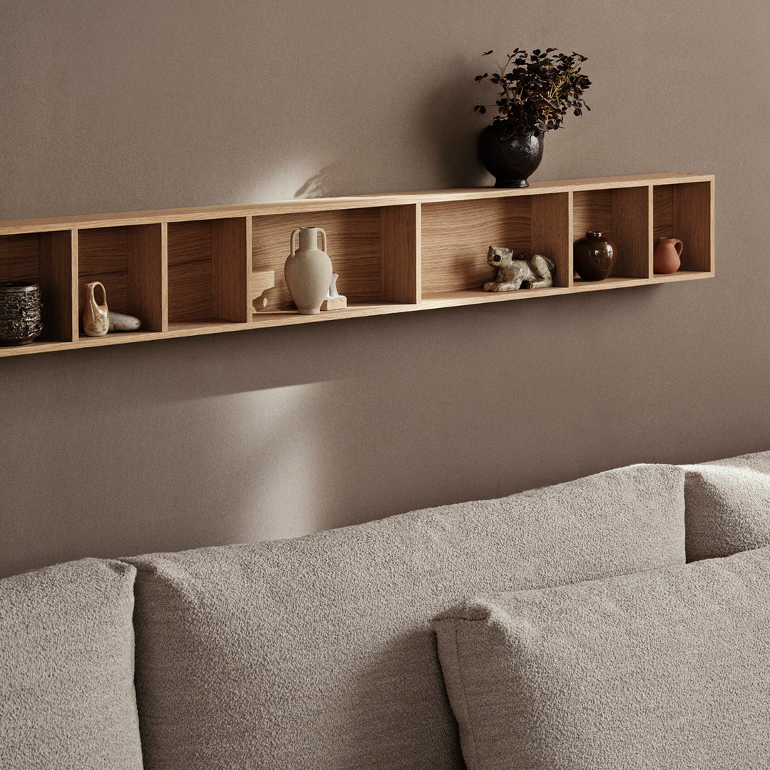"Light wood shelving with decorative objects and a soft grey couch, featuring textured upholstery and neutral wall colors."