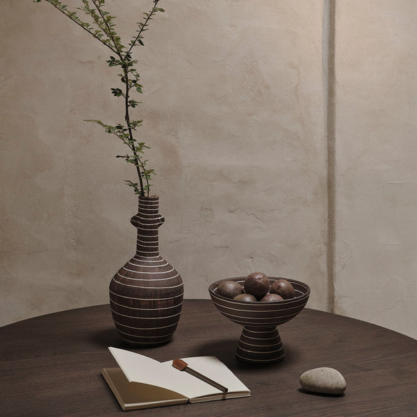 Brown striped ceramic vase and bowl on a wooden table, complemented by soft beige and earthy tones in the background.