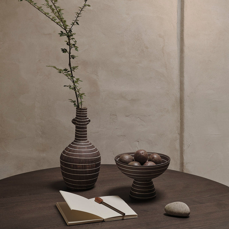 Brown striped ceramic vase and bowl on a wooden table, complemented by soft beige and earthy tones in the background.