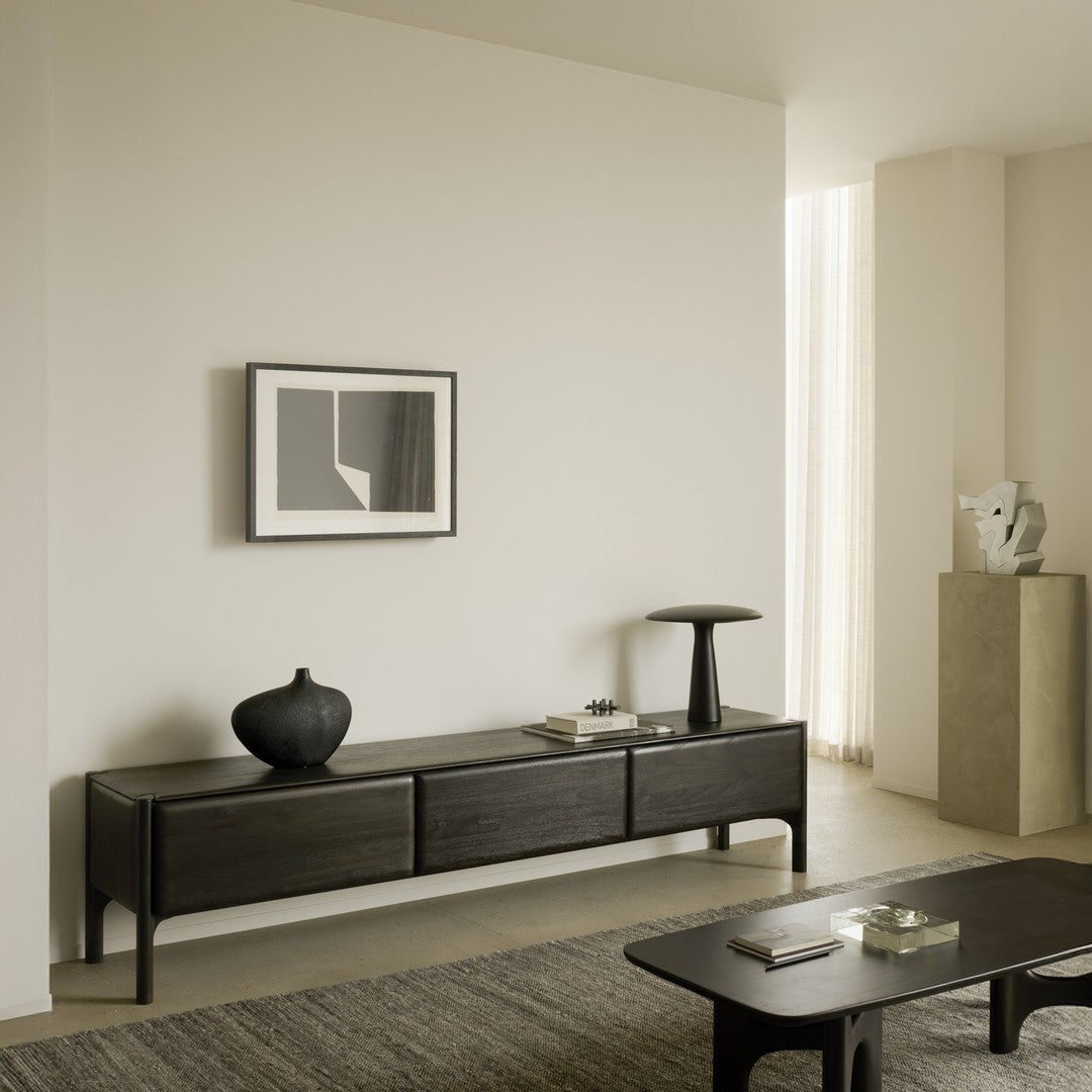Black minimalist sideboard with smooth surfaces, paired with neutral beige and gray tones in a modern interior setting.