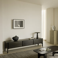 Black minimalist sideboard with smooth surfaces, paired with neutral beige and gray tones in a modern interior setting.
