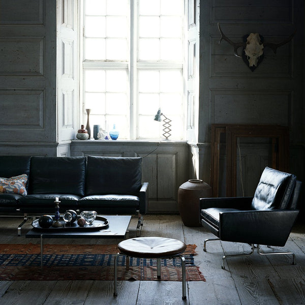 "Stylish black leather furniture with a blue geometric rug and natural wood accents in a modern living space."