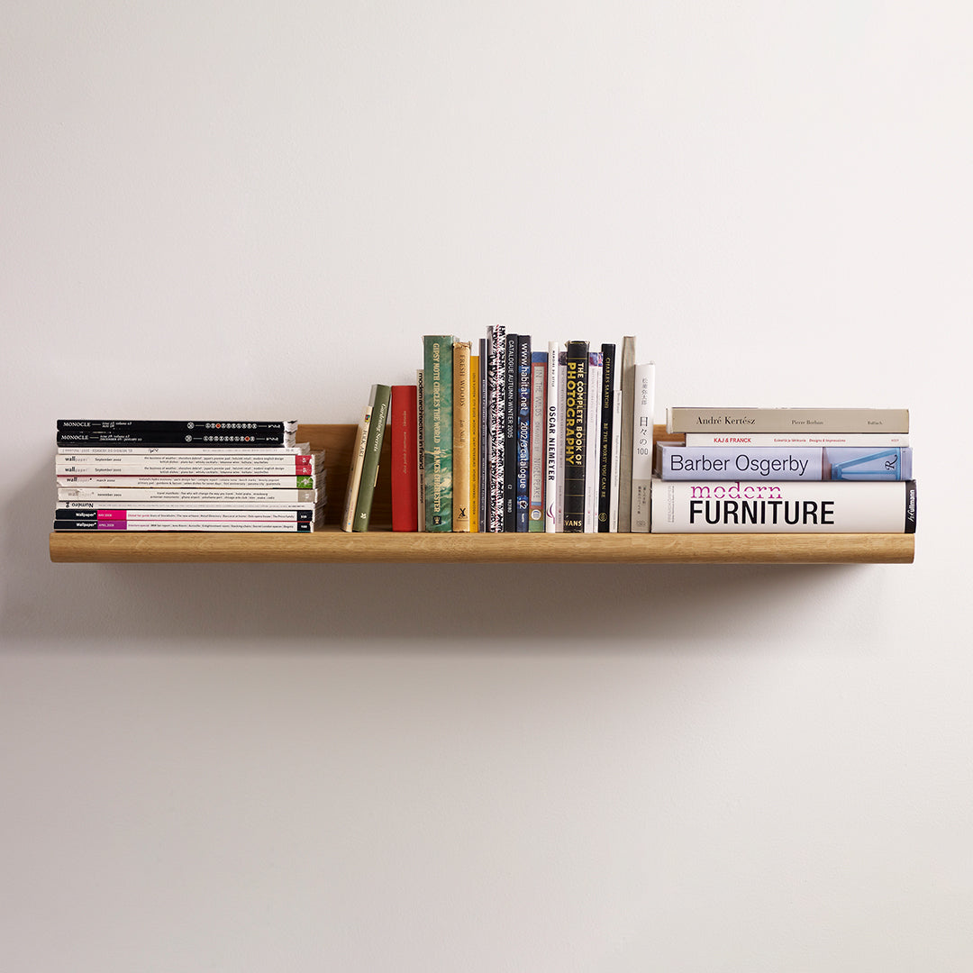Natural wood shelf with a smooth finish, displaying a colorful assortment of books in varying hues and patterns.