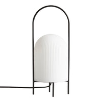 White ribbed lamp with a sleek black metal frame and curved top, perfect for modern decor styles.